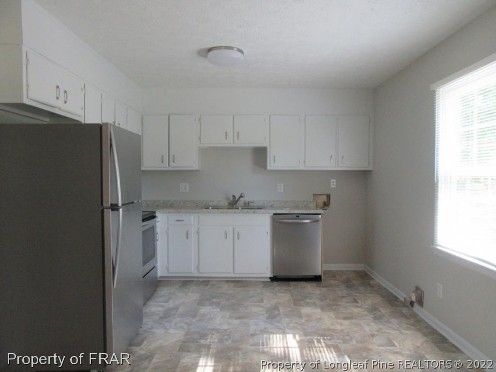 5947 Spinner Road Hope Mills, NC 28348 - Photo 12 of 31 a kitchen with granite countertop white cabinets and refrigerator