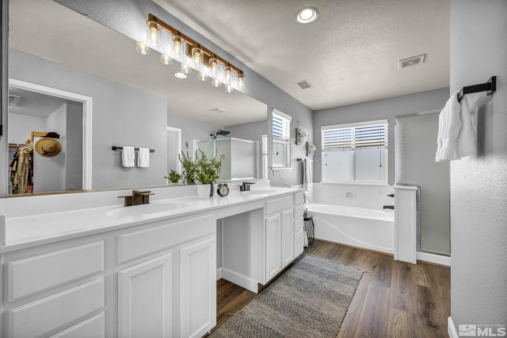 485 Sondrio Court Reno, NV 89521 - Photo 20 of 40 a bathroom with a double vanity sink a mirror a bathtub and a shower