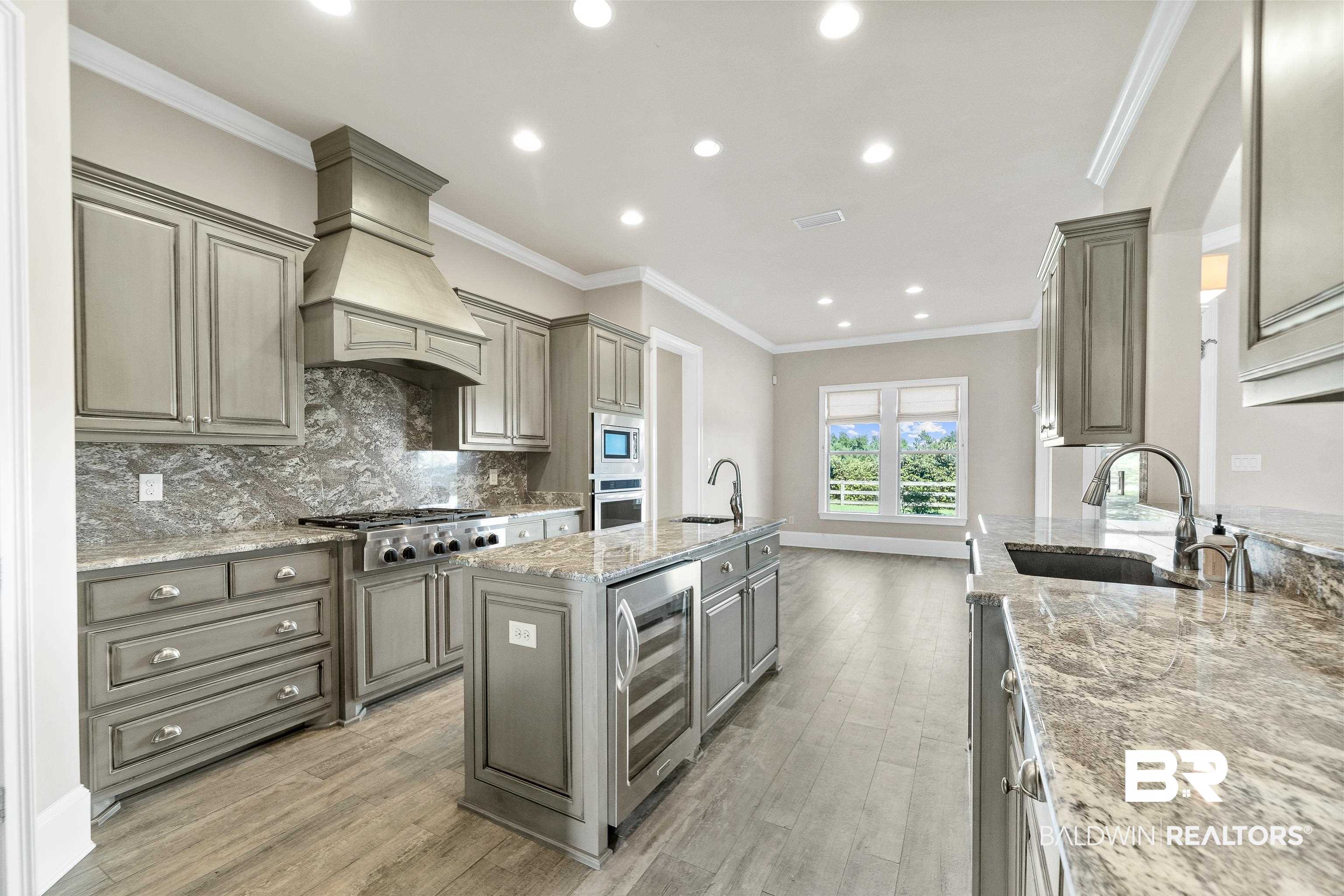 17663 Burwick Loop Fairhope, AL 36532 - Photo 16 of 41 Kitchen featuring appliances with stainless steel finishes, light stone counters, beverage cooler, premium range hood, and hardwood / wood-style floors
