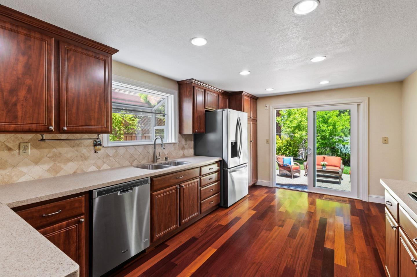 43643 Skye Road Fremont, CA 94539 - Photo 6 of 16 a kitchen with stainless steel appliances granite countertop wooden floors a stove a sink and a window