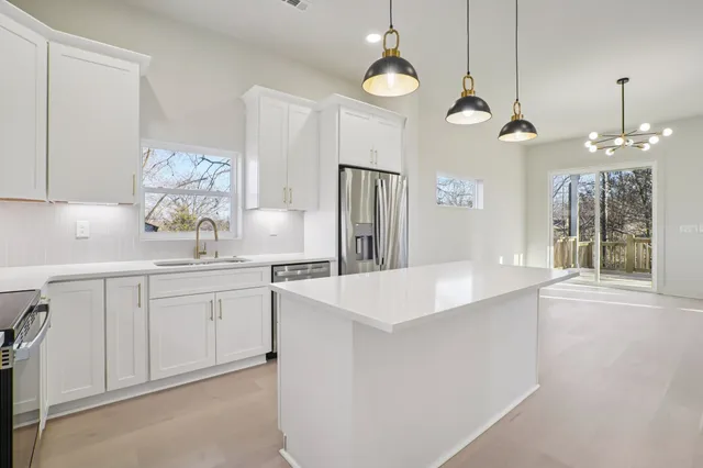 a large white kitchen with a sink a refrigerator and a stove top oven