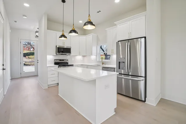 a kitchen with stainless steel appliances granite countertop a refrigerator a stove a sink and a refrigerator