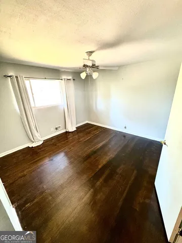 a view of a room with wooden floor and a ceiling fan
