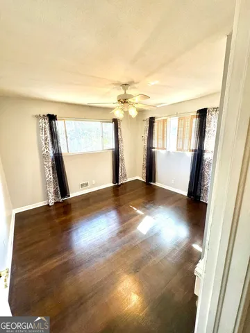 a view of empty room with wooden floor and fan