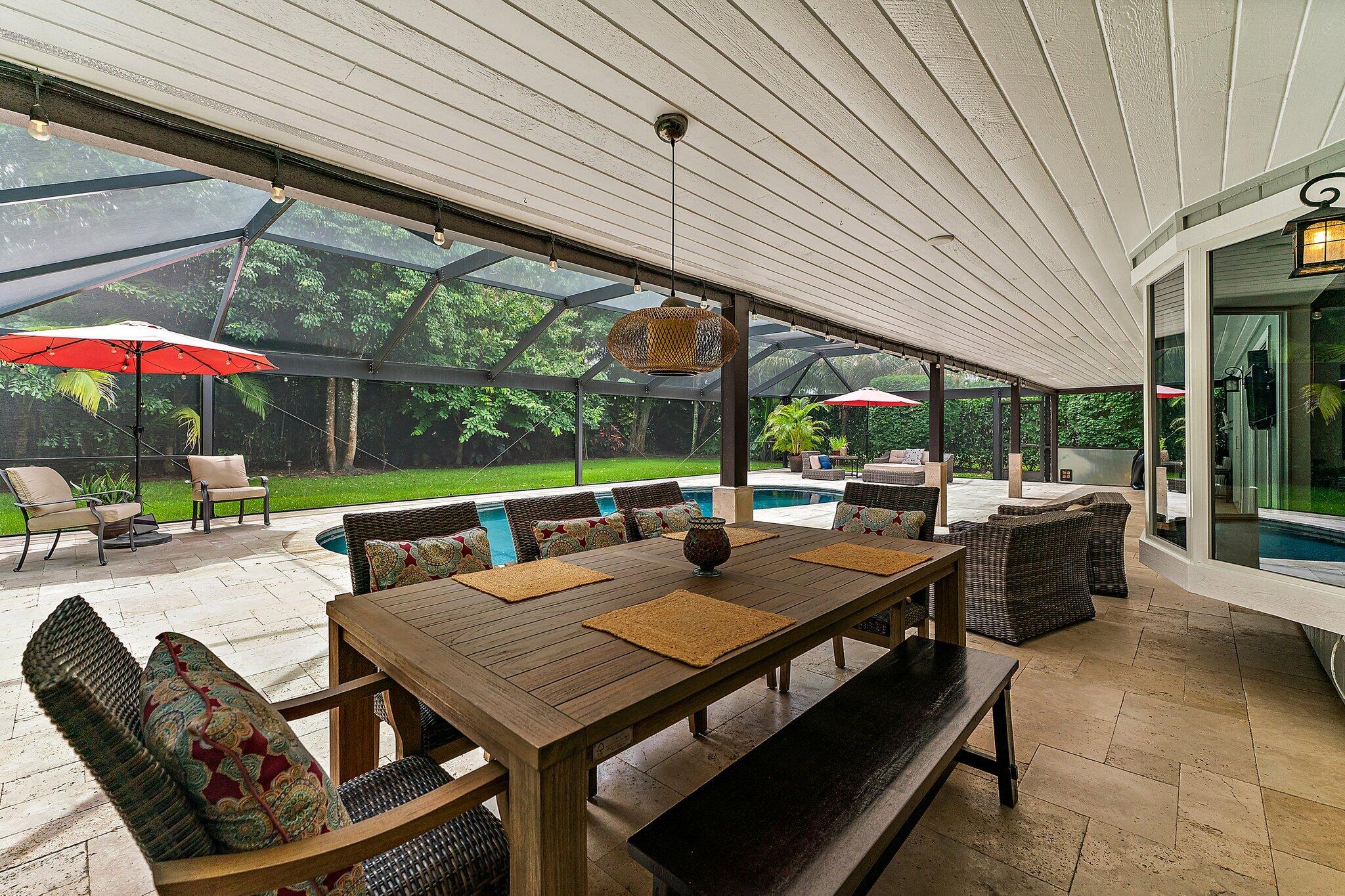 19546 Red Gum Trail Jupiter, FL 33458 - Photo 31 of 42 a view of a patio with a dining table and chairs under an umbrella