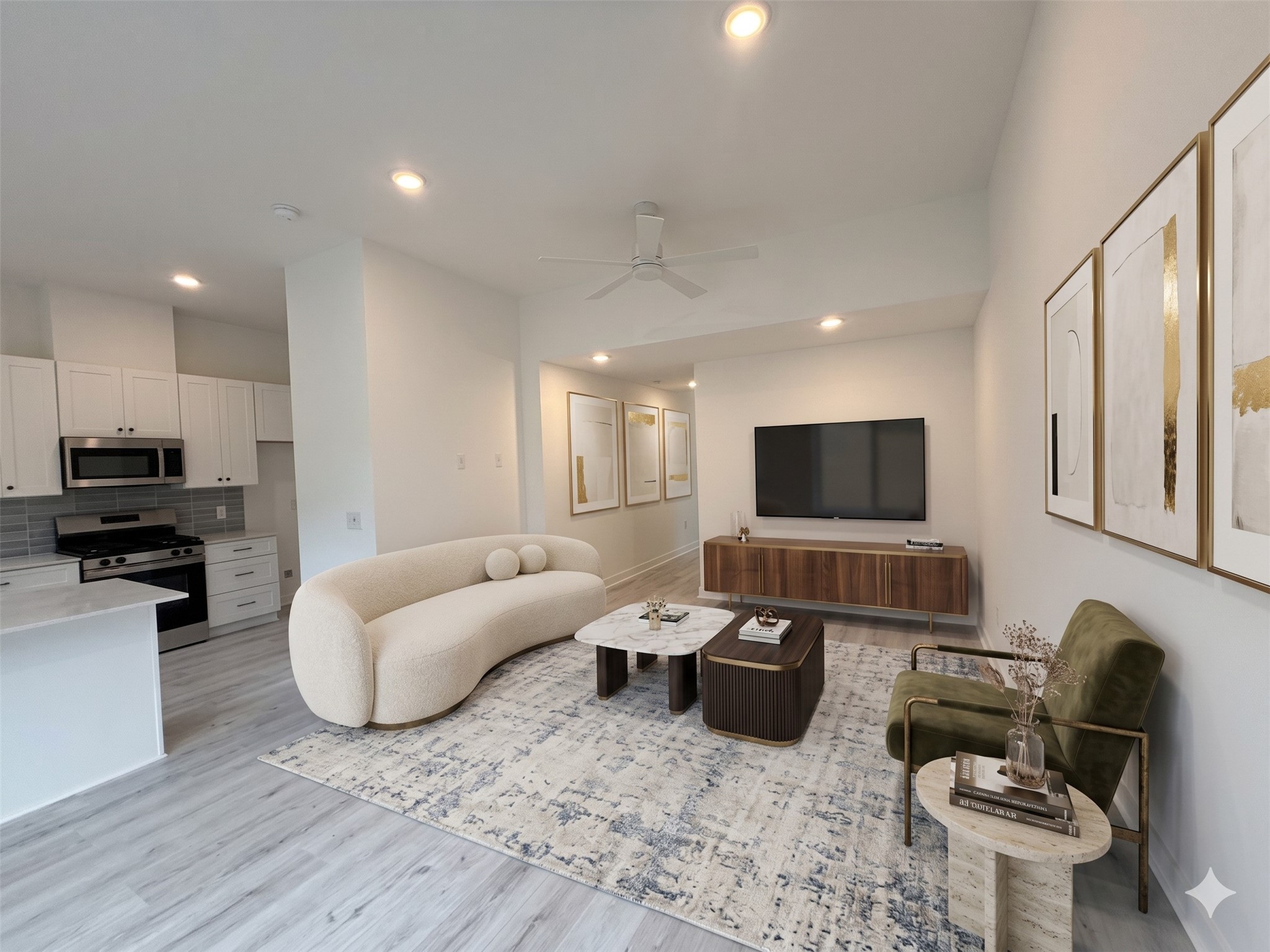 This modern living area features an open layout with light wood flooring and a neutral palette. It includes a cozy curved sofa, a stylish TV unit, and a chic kitchen with stainless steel appliances.