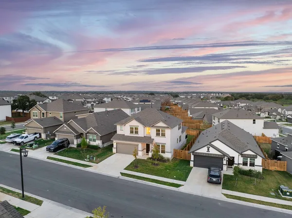 an aerial view of residential houses with cars parked on the road