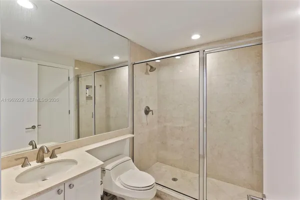 a bathroom with a shower sink vanity mirror and toilet