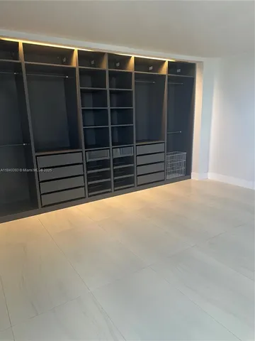 a view of an empty room with furniture and a window