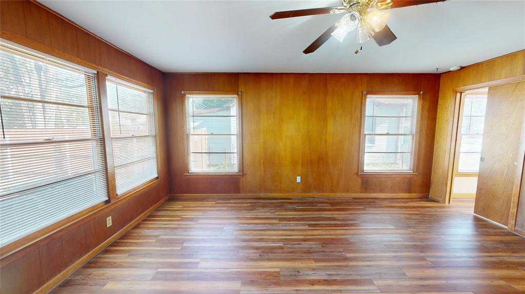 3125 McFerrin Avenue Waco, TX 76708 - Photo 14 of 36 Unfurnished room with wood walls, wood finished floors, plenty of natural light, and ceiling fan