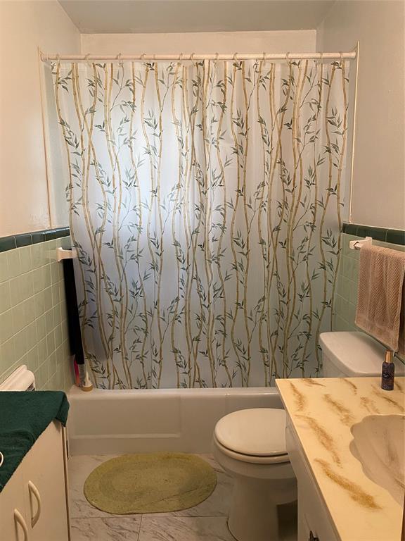 3125 McFerrin Avenue Waco, TX 76708 - Photo 24 of 36 Bathroom with tile walls, vanity, shower / tub combo, and a wainscoted wall