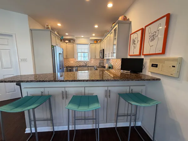 a kitchen with stainless steel appliances a dining table chairs and a refrigerator