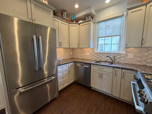 a kitchen with granite countertop stainless steel appliances a refrigerator a sink and cabinets
