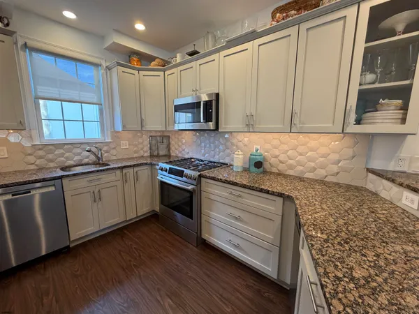 a kitchen with granite countertop a sink cabinets and stainless steel appliances