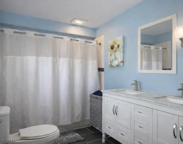 a bathroom with a granite countertop sink toilet and mirror
