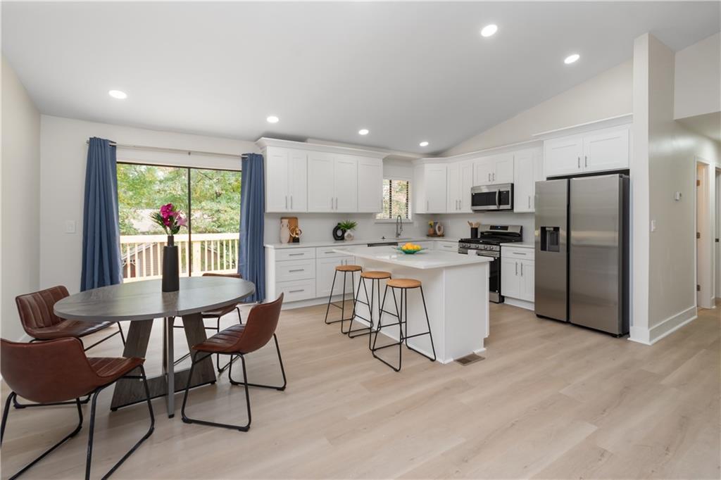 2432 Mistletoe Lane Southwest Snellville, GA 30039 - Photo 12 of 42 a kitchen with stainless steel appliances a dining table chairs refrigerator and microwave