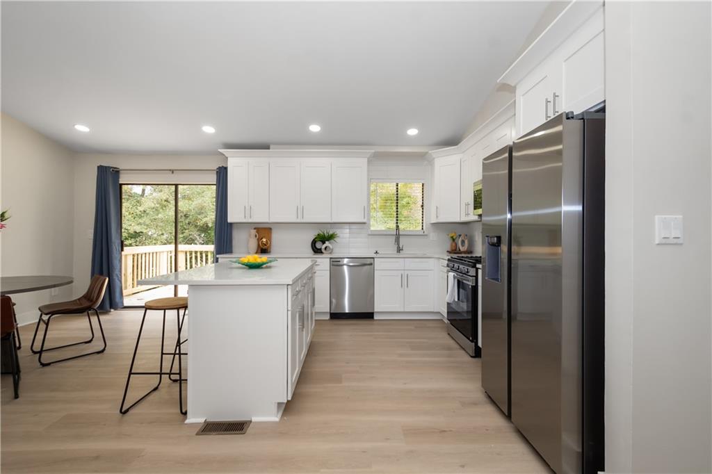 2432 Mistletoe Lane Southwest Snellville, GA 30039 - Photo 6 of 42 a kitchen with a refrigerator a sink dishwasher with a dining table and chairs