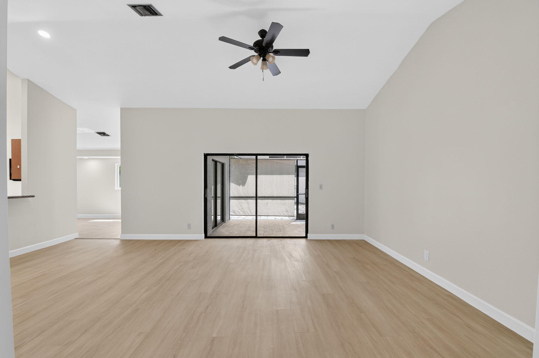 21070 Woodspring Avenue Boca Raton, FL 33428 - Photo 5 of 30 an empty room with wooden floor chandelier fan and windows