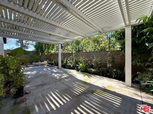 a view of a patio with table and chairs under an umbrella with plants