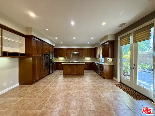 a large kitchen with stainless steel appliances kitchen island granite countertop a refrigerator and a sink