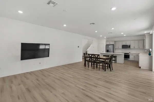 a view of a kitchen with kitchen island a sink dishwasher a dining table and chairs with wooden floor