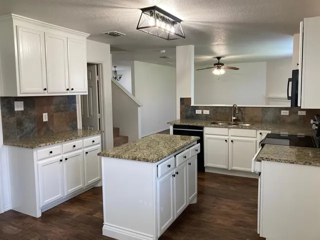 a kitchen with granite countertop a sink stove and cabinets
