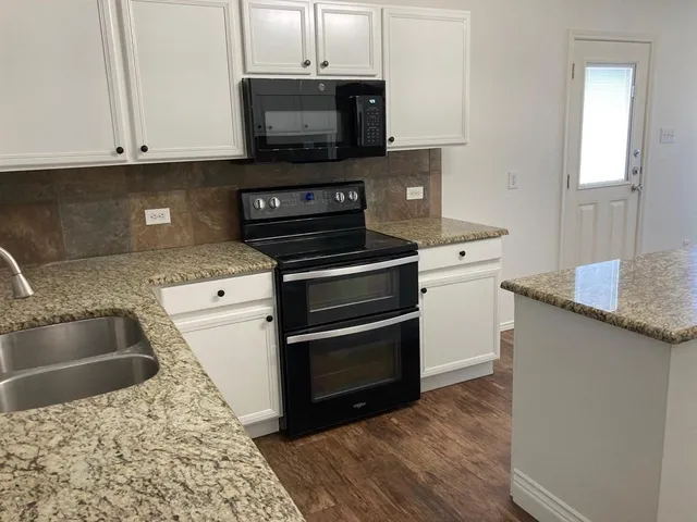 a kitchen with granite countertop a stove and a sink