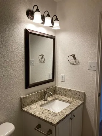 a bathroom with a granite countertop sink and a mirror