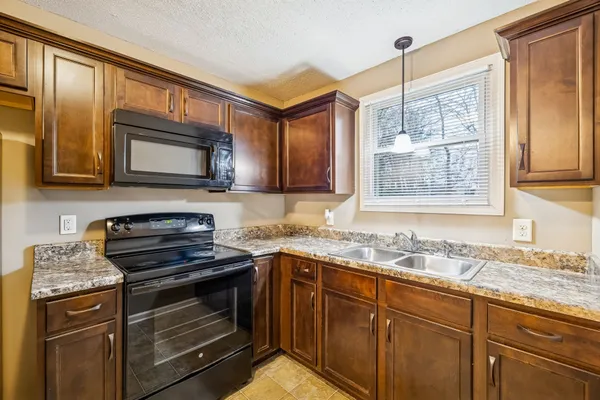 a kitchen with granite countertop a stove sink and microwave