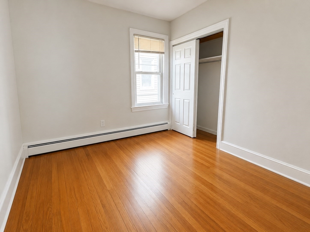 631 Walnut Street, Unit 1 Fall River, MA 02720 - Photo 8 of 12 an empty room with wooden floor and windows with curtains