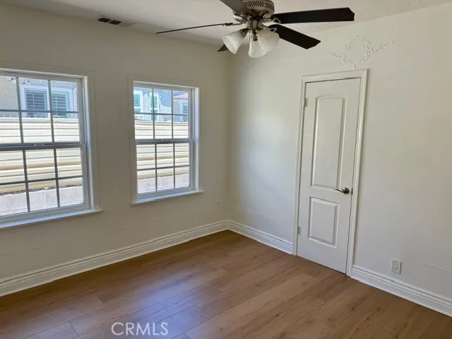 an empty room with wooden floor closet and windows