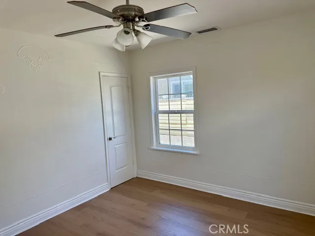 an empty room with wooden floor chandelier fan and windows