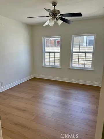 an empty room with wooden floor fan and windows
