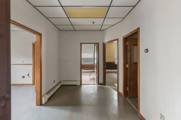 a view of a hallway with wooden floor and a bathroom