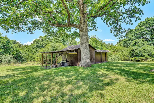 an aerial view of residential house with outdoor space and trees all around