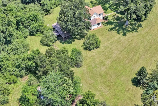 an aerial view of residential house with outdoor space and trees all around
