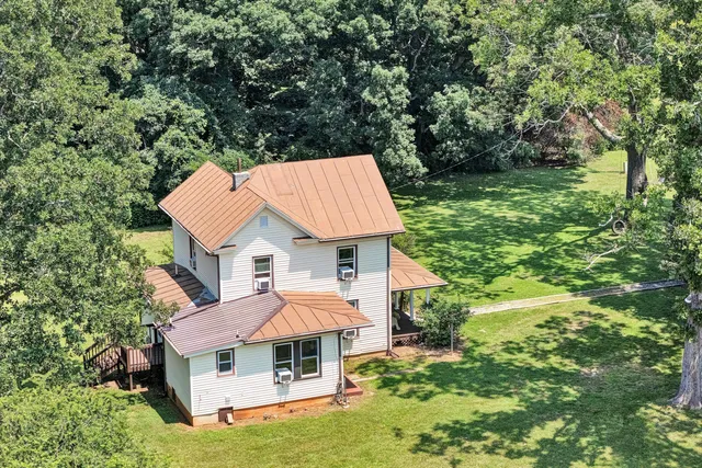 an aerial view of a house with swimming pool and large trees