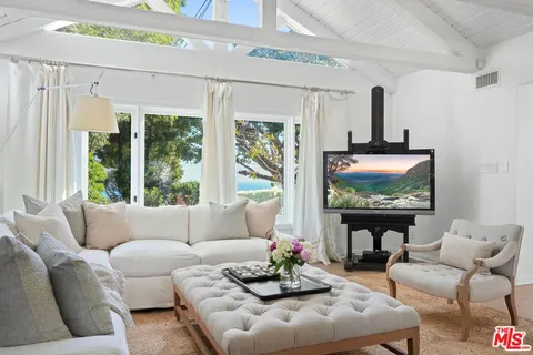a living room with furniture a flat screen tv and a floor to ceiling window