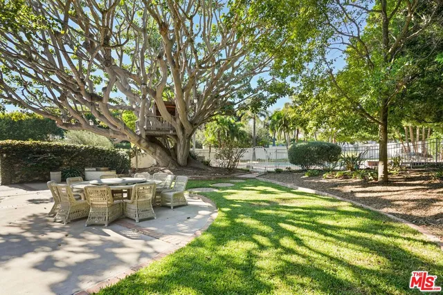 a view of a patio with table and chairs and couches with large trees