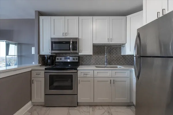 a kitchen with white cabinets and stainless steel appliances
