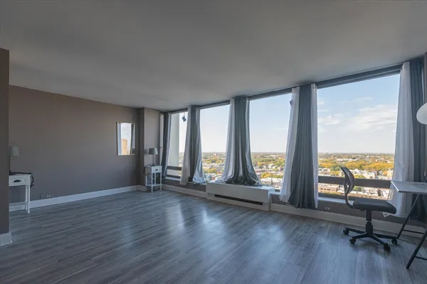 a view of an empty room with wooden floor and a window