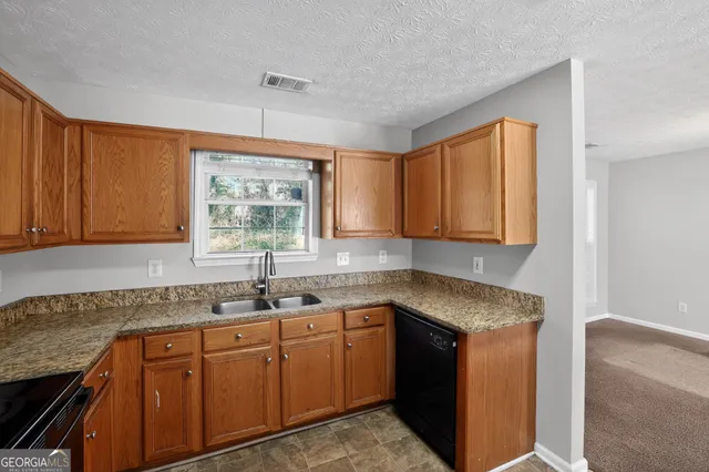 a kitchen with granite countertop white cabinets sink and window