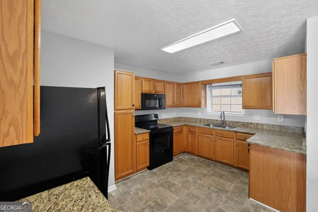 a kitchen with granite countertop stainless steel appliances a sink a refrigerator a counter top space and cabinets