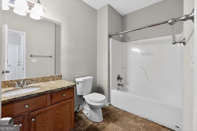 a bathroom with a granite countertop sink toilet a shower and a mirror