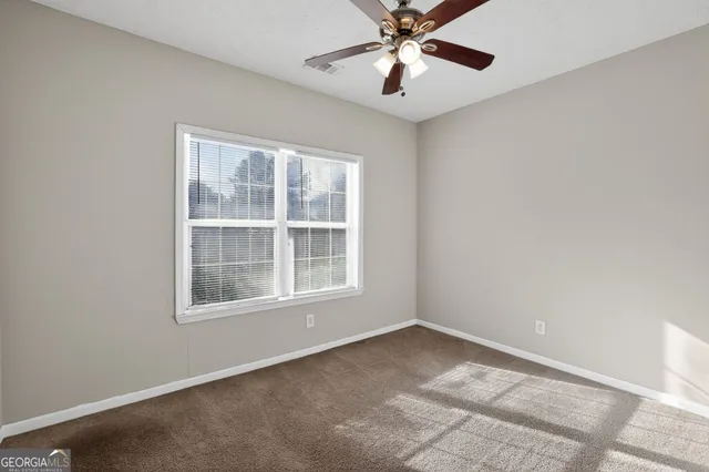 an empty room with a window and a fan