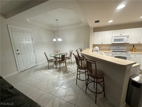a kitchen with a dining table chairs and white appliances