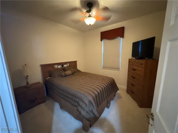 a bedroom with a bed and a flat tv screen on the dresser