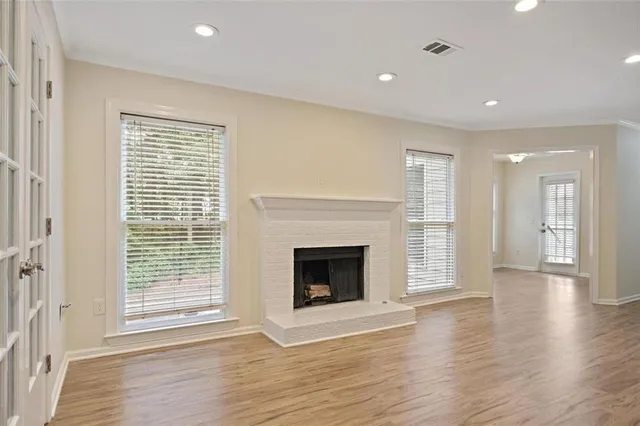 a view of an empty room with wooden floor fireplace and a window