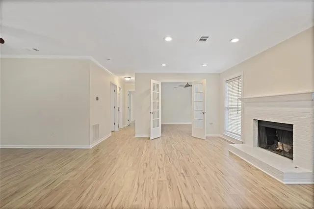 a view of an empty room with wooden floor fireplace and a window