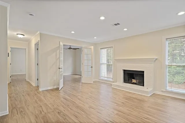 a view of an empty room with wooden floor fireplace and a window
